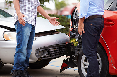 Une voiture rouge a percutée une voiture grise, deux hommes discutent devant l'accident.