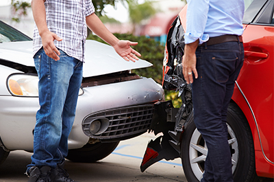 Assurance auto-risques-aggravés Une voiture rouge a percutée une voiture grise, deux hommes discutent devant l'accident.